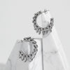 Gold-tone hoop earrings wrapped with silver ring accents, displayed on a white surface beside a marble stones.