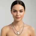Woman wearing a silver necklace with a gray background