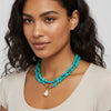 Woman wearing a turquoise necklace with a white background