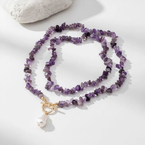 Purple beaded necklace with a gold clasp on a light gray background