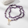 Purple beaded necklace with a gold clasp on a light gray background