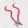 A beaded necklace with bright pink round beads, gold-tone chain and connectors, and three dangling charms: a turquoise heart, a gold starfish, and a pink fish, displayed on a clean white background.
