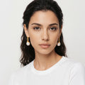 Woman wearing pearl earrings against a plain background