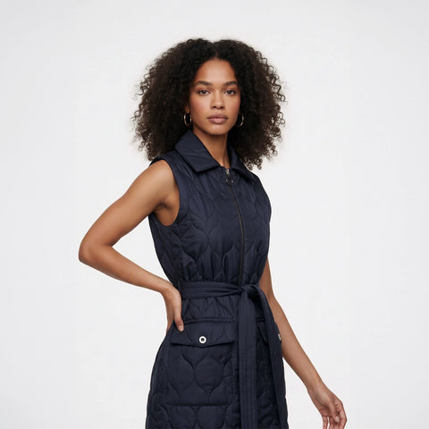 Person wearing a navy quilted vest over a white sweater on a white background