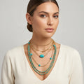 Woman wearing multiple necklaces with turquoise beads on a neutral background