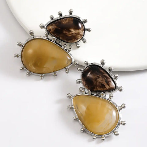Pair of earrings with brown and yellow stones on a white background