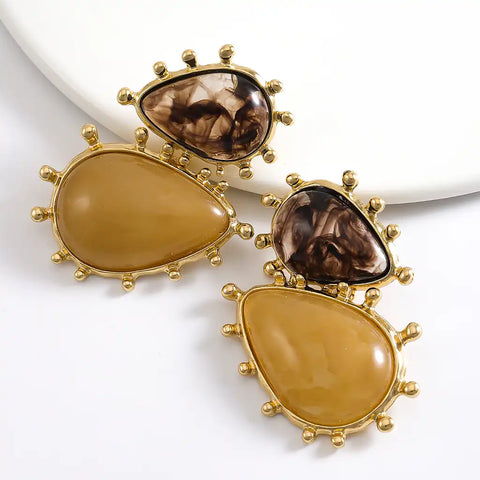 Pair of gold earrings with brown teardrop-shaped stones on a white background