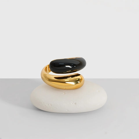 Gold and black ring on a white stone with a plain background
