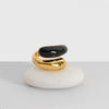 Gold and black ring on a white stone with a plain background