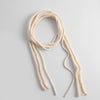 A long cream-colored knit scarf with long, thin tails, arranged in a loose loop on a light gray background.