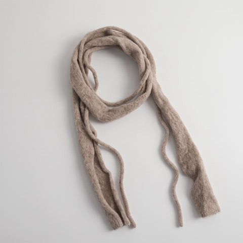 A textured, fuzzy knit scarf in a light taupe-beige color, styled in a loose loop on a clean, light gray background.