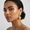 Woman wearing sunflower-shaped earrings on a plain background