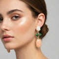 Pair of earrings with gold frames and colorful stones on a white surface