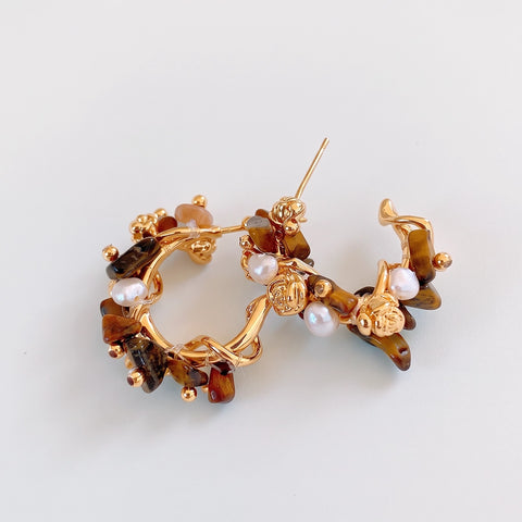 A pair of gold hoop earrings decorated with irregular brown amber stones, small white pearls, and tiny gold beads, displayed on a clean white background.