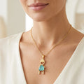 Gold necklace with a blue pendant worn by a person in a white outfit.