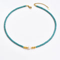 Turquoise beaded necklace with gold accents on a white background