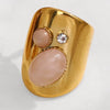 Gold ring with pink stone and clear gem on a white background