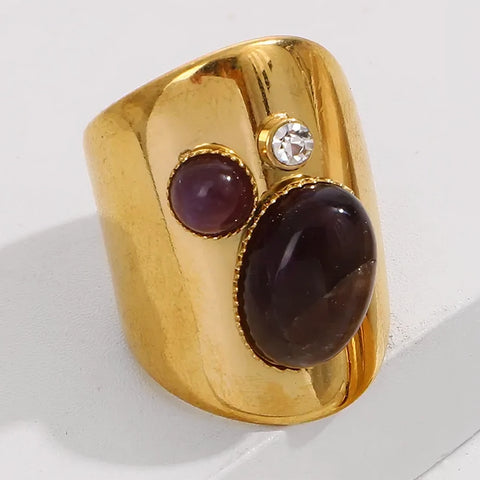Gold ring with purple stones and a diamond on a white background