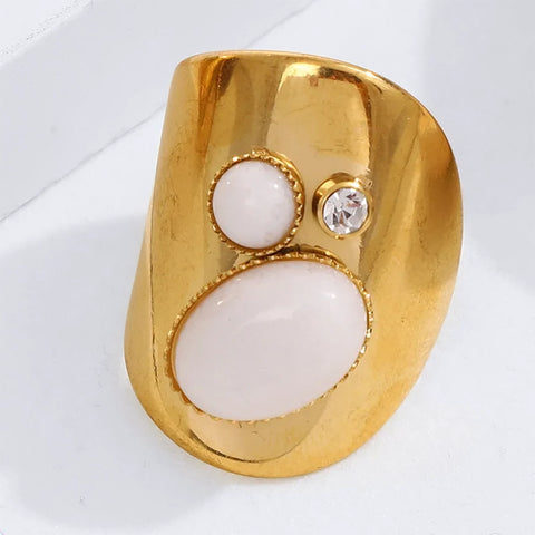 Gold ring with two white stones and a clear gemstone on a white background